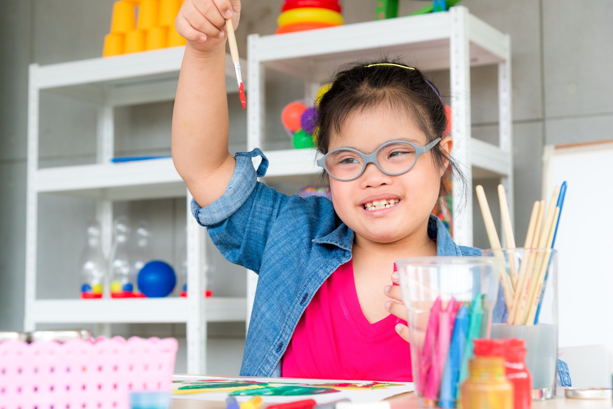 Young autism disabled child complex genetic disorders kid drawing a picture by watercolor.